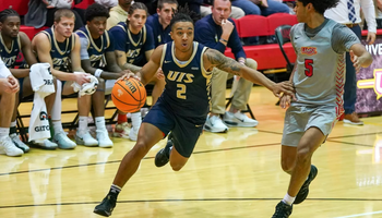 Jordan Rice playing basketball in blue UIS uniform