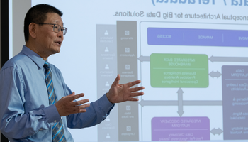 Man giving a presentation with a slide in the background.