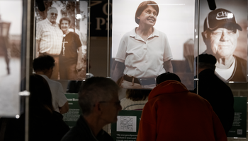 Exhibition with large portraits of people, dark silhouettes in foreground.