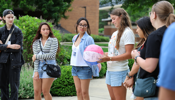 Group of young adults outdoors, one holding a colorful beach ball.