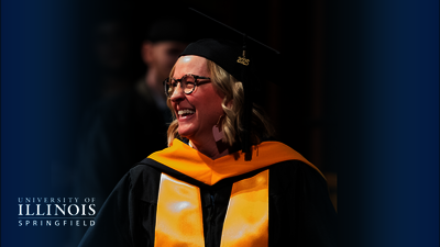 Graduate in cap and gown smiling during ceremony.