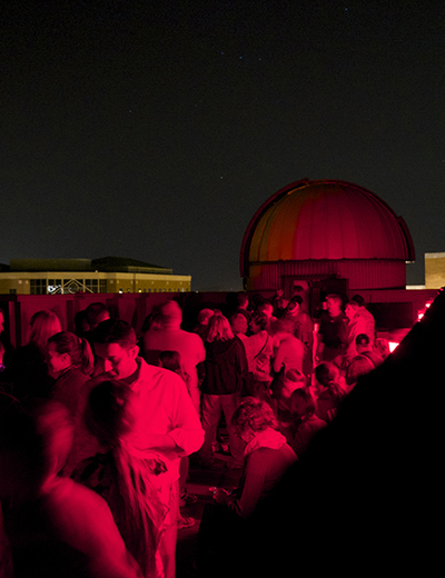 People gather for a Star Party on the roof of Brookens Library at night.