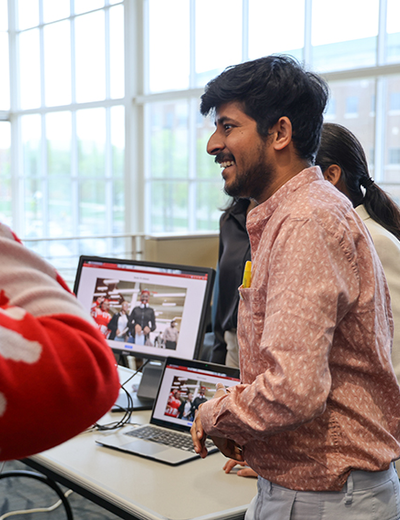 Student smiles while presenting a project on a laptop during a campus event.