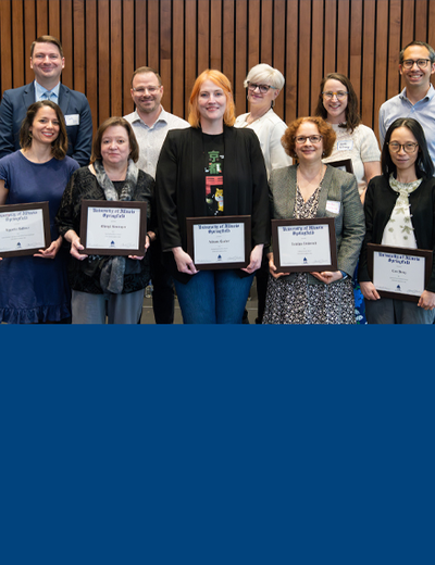 Ten faculty members pose for a photo holding their awards. 