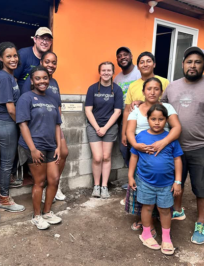 A group of UIS students and local residents stand in front of a newly built home during a service trip in Guatemala.