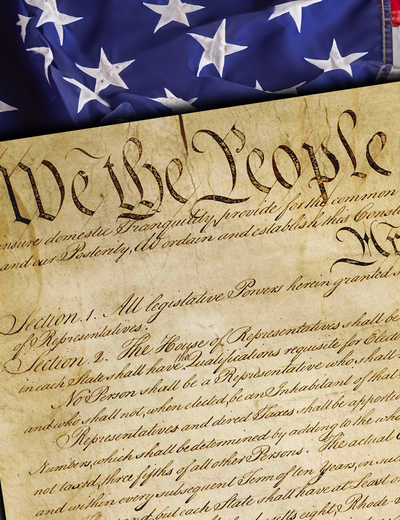 Close-up of the United States Constitution with the words “We the People” visible, placed over an American flag background.
