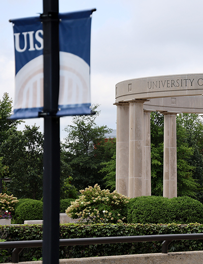 University Colonnade and a UIS banner, overcast sky.