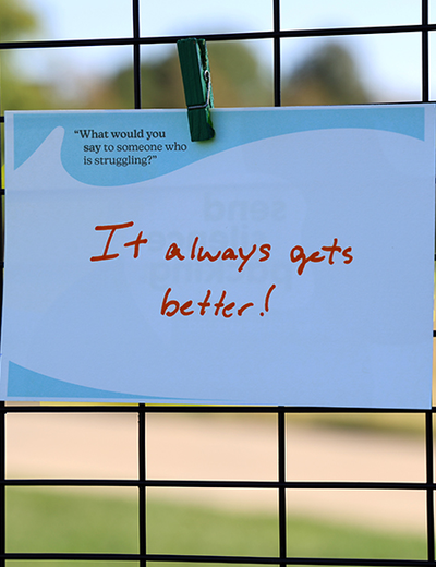 Sign clipped to a fence reads, "It always gets better!"