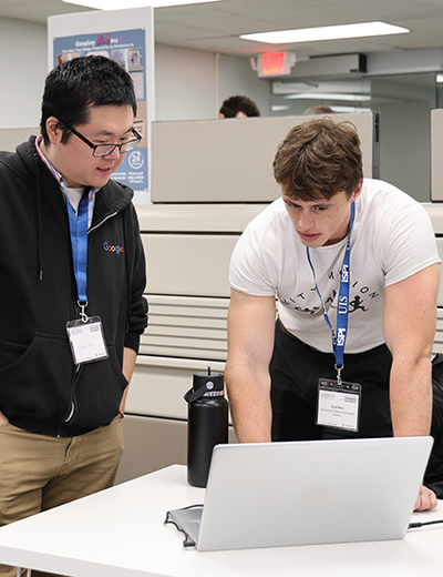 Two men collaborating at a laptop in an office setting.