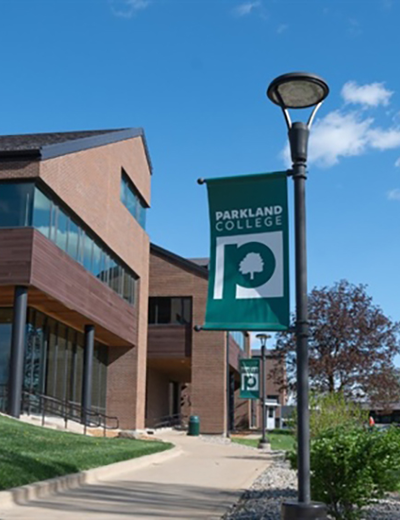 Parkland College banner on a lamppost, clear blue sky.