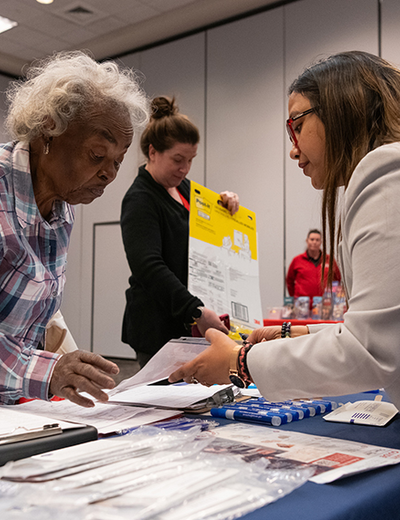 People interacting at a table with documents and supplies.