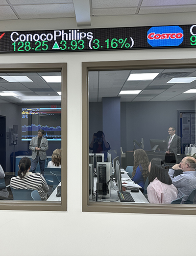 People in a conference room watching a financial presentation.