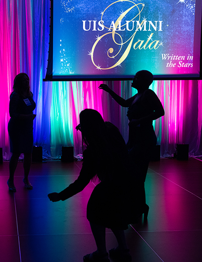 Silhouetted dancers at a colorful gala event.