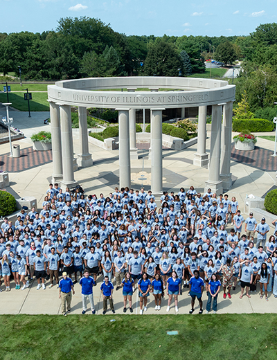 Large group of people in front of a circular monument with columns.