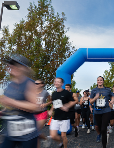 Runners passing a blue inflatable arch, blurred motion.