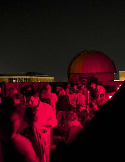 Crowd under red lighting at night, with dome in the background.