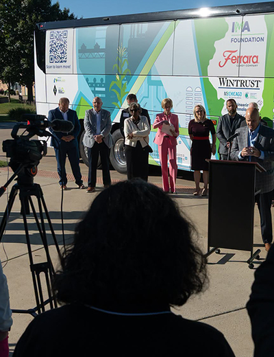 People standing in front of a brightly colored bus, with camera setup in foreground.