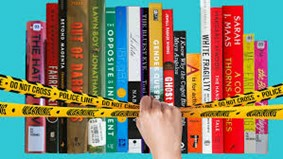 A hand ripping caution tape off a stack of books
