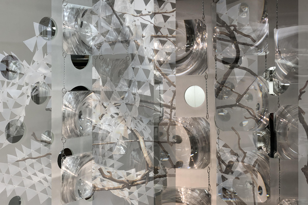 composited images of tree branches with paper cutouts over mirrors hanging from chains