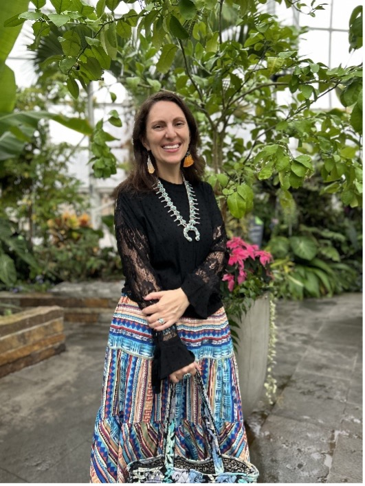 Picture of a woman standing with a colorful skirt in front of a tree