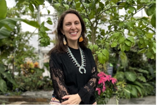 Picture of a woman standing in front of greenery