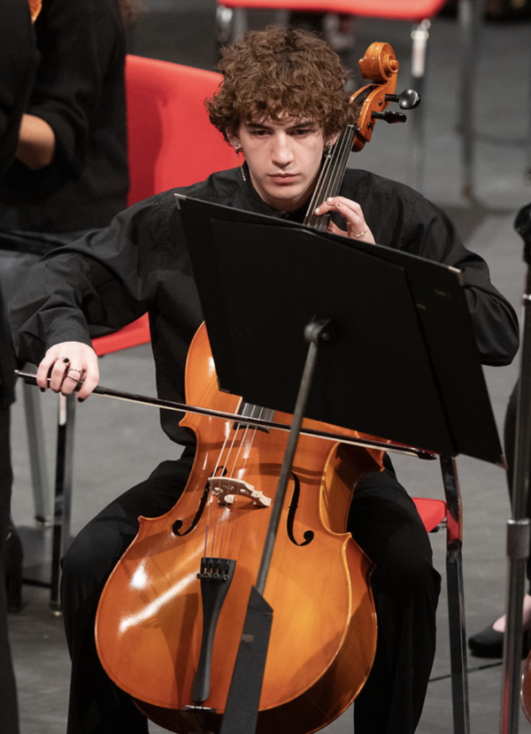 Cellist playing on stage, focused.
