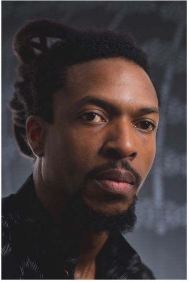 Dark-lit portrait of a serious-looking man with a black shirt.