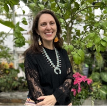 Picture of a woman standing in front of greenery