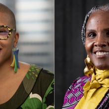 Two women smiling, one with glasses, bright earrings, and the other in a patterned outfit.