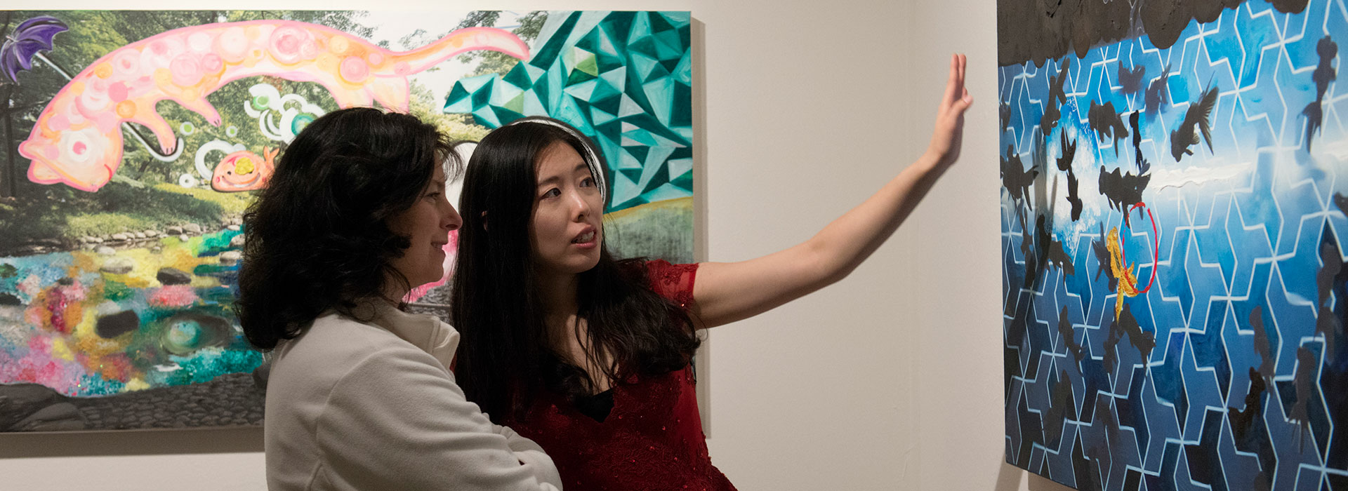 Two women discussing a painting at the UIS Visual Arts Gallery