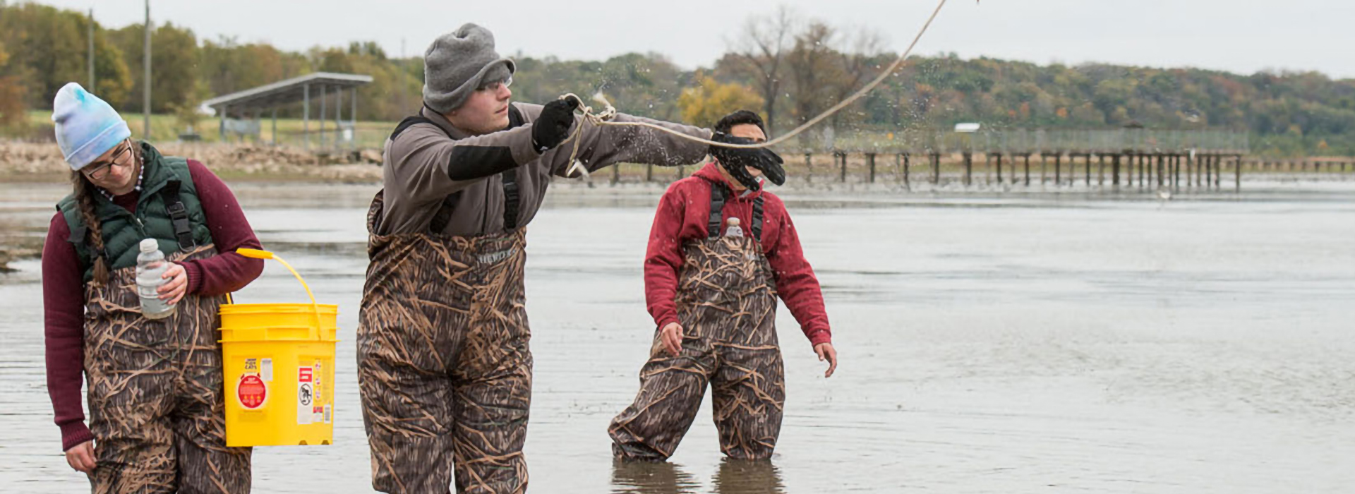 people standing in the water with camouflage overalls