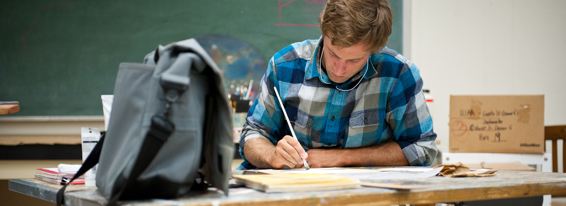 student sitting at a table in an art studio painting