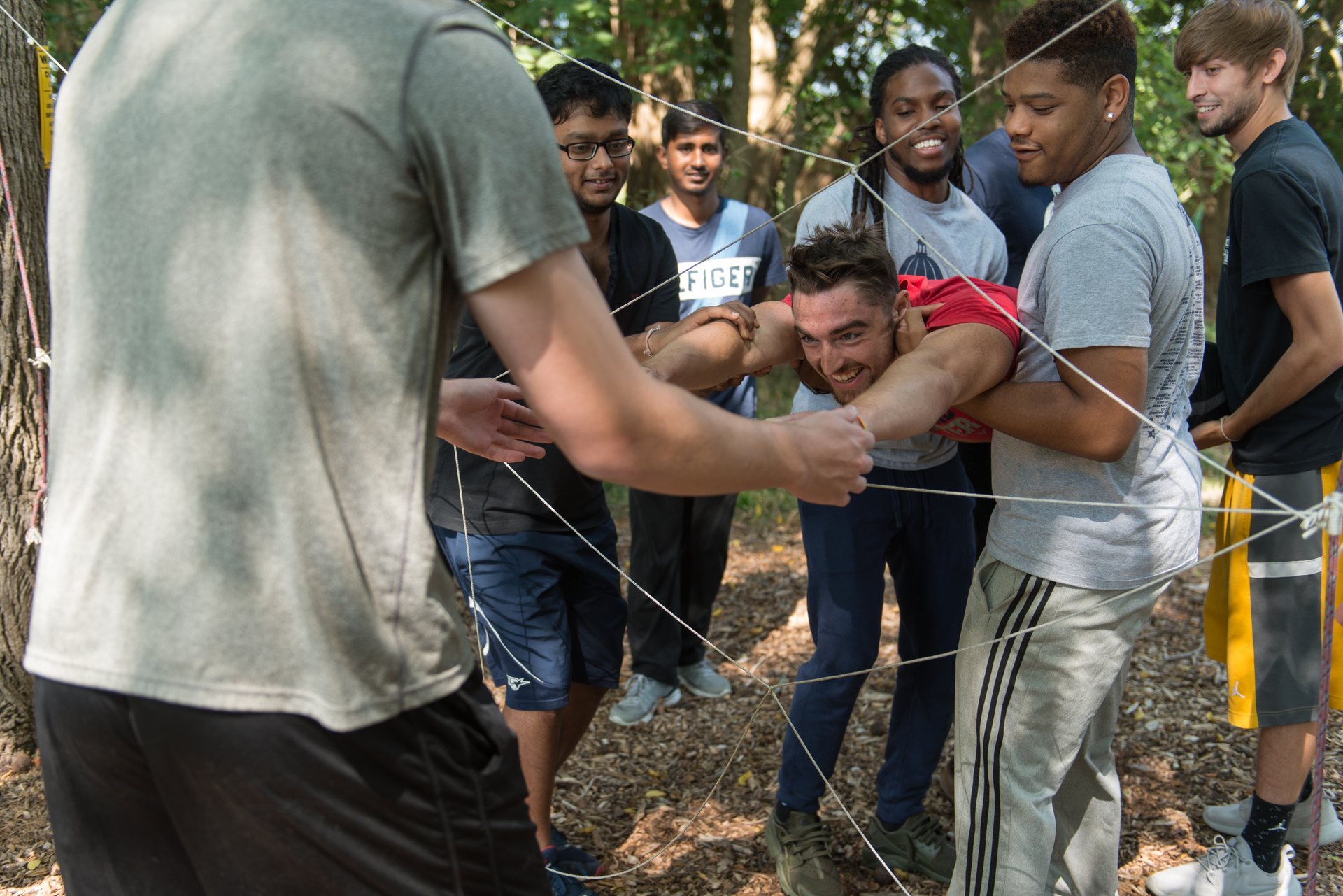 Students work together to lift another student through a rope web at the UIS Challenge Course.