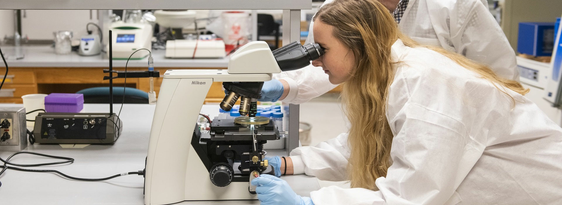 student and professor looking into microscope