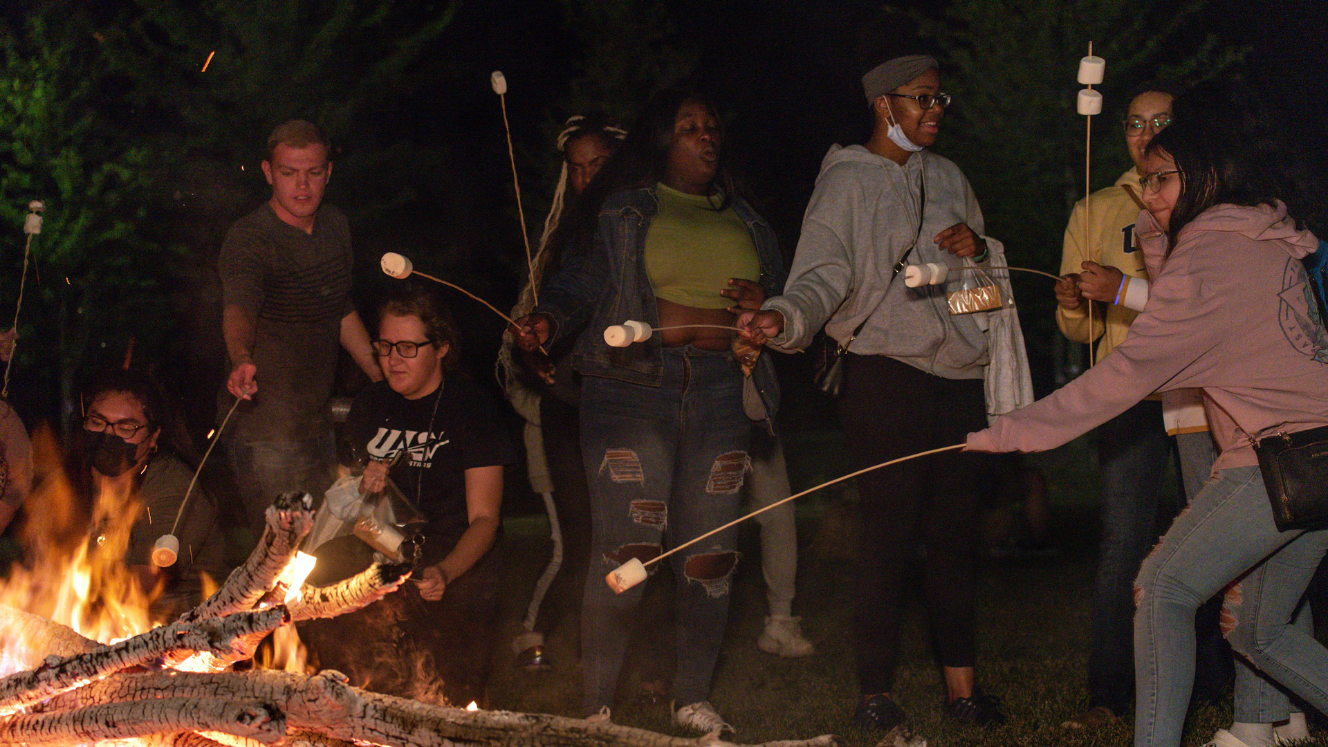 Students roasting marshmallows at a bonfire