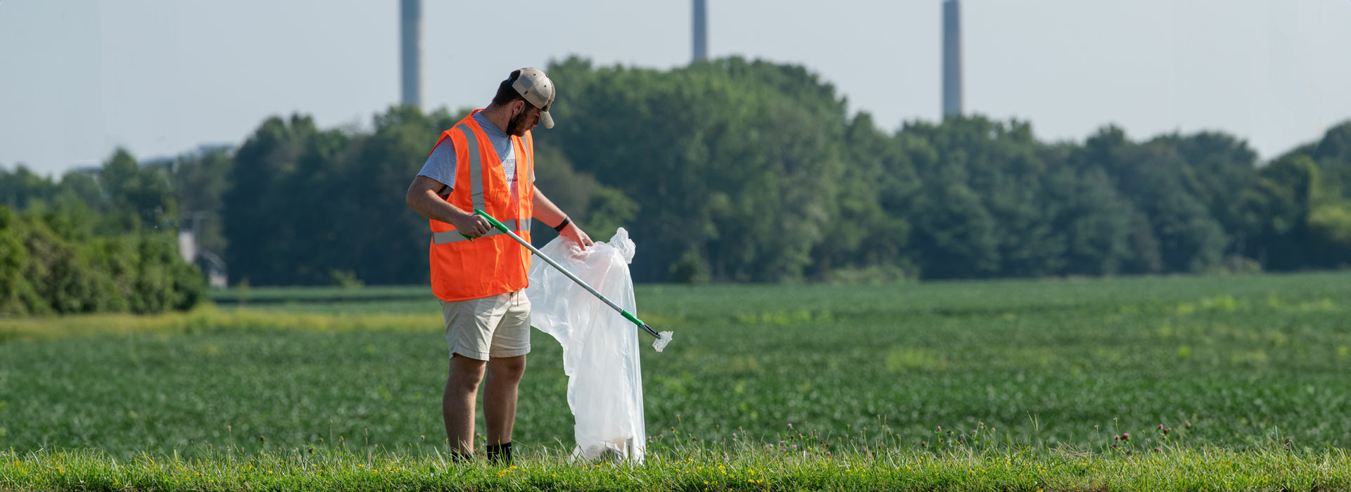 a volunteer picking up trash in a field