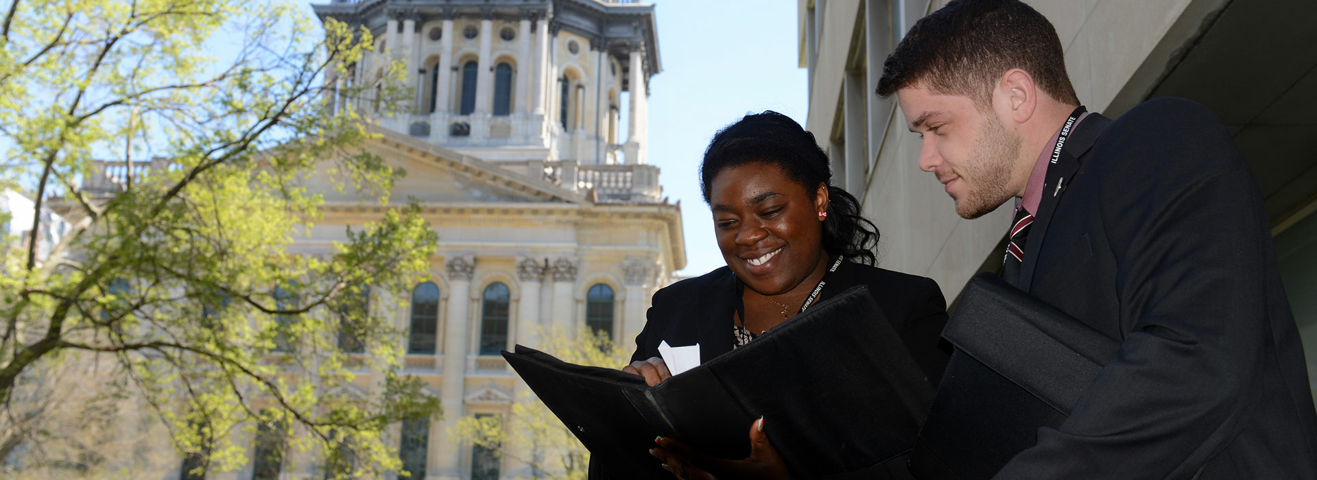two lawmaker students looking over paperwork on the steps of the state capitol