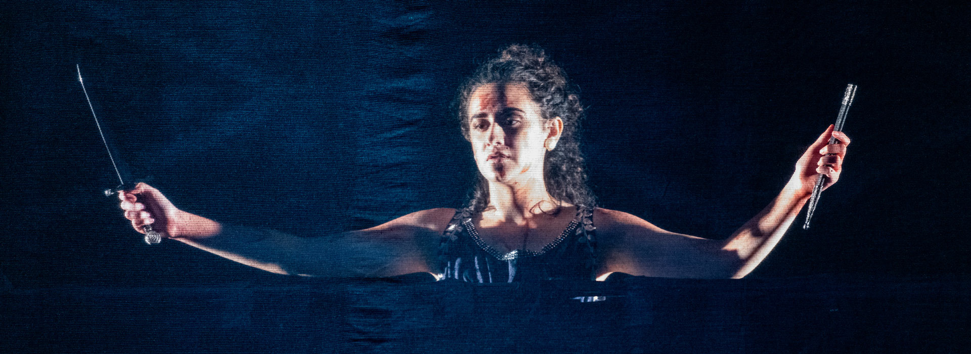 a woman on stage holding knives with a look of despair