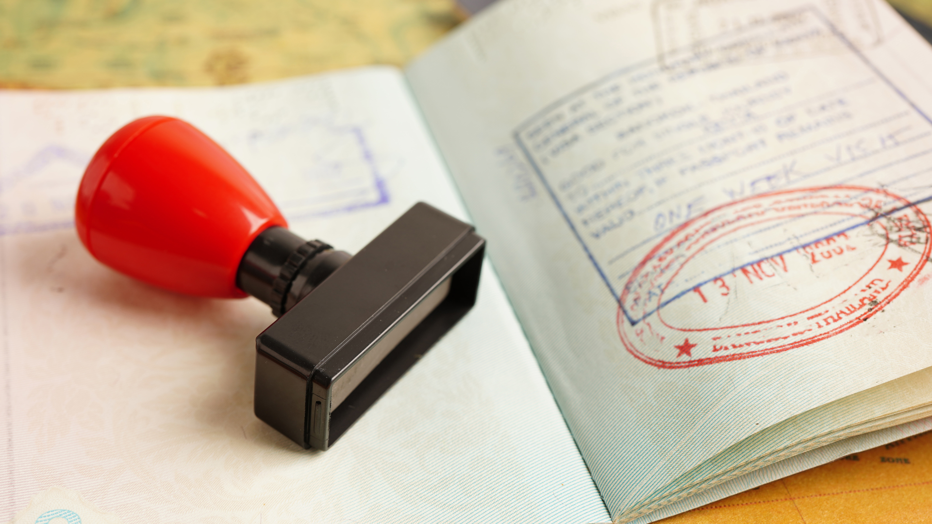 Up-close view of a stamped passport. Beside it is a black stamper with a red handle.