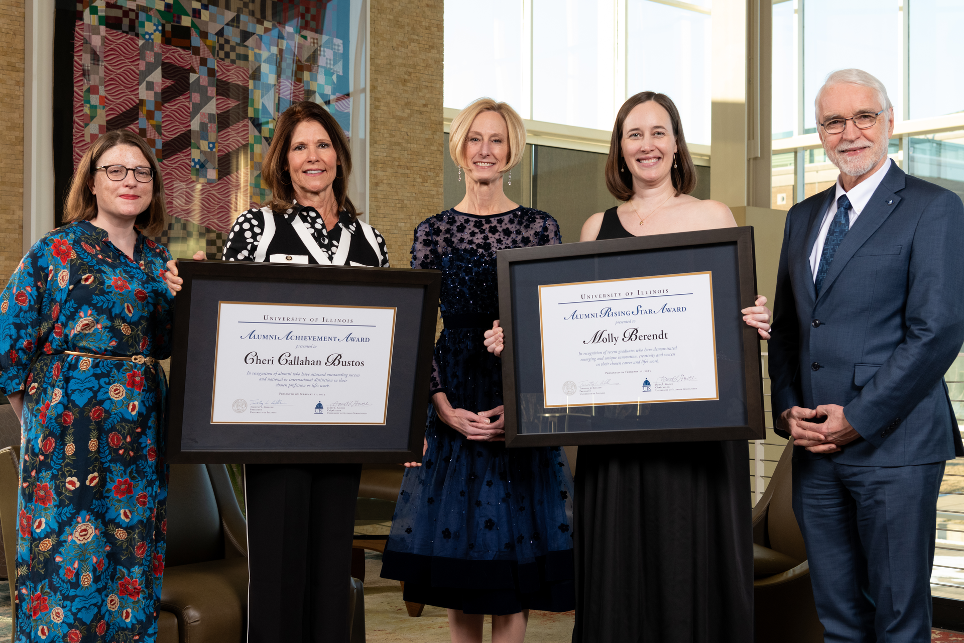 two awardees holding their awards pose with UIS alumni board chair, chancellor and system president