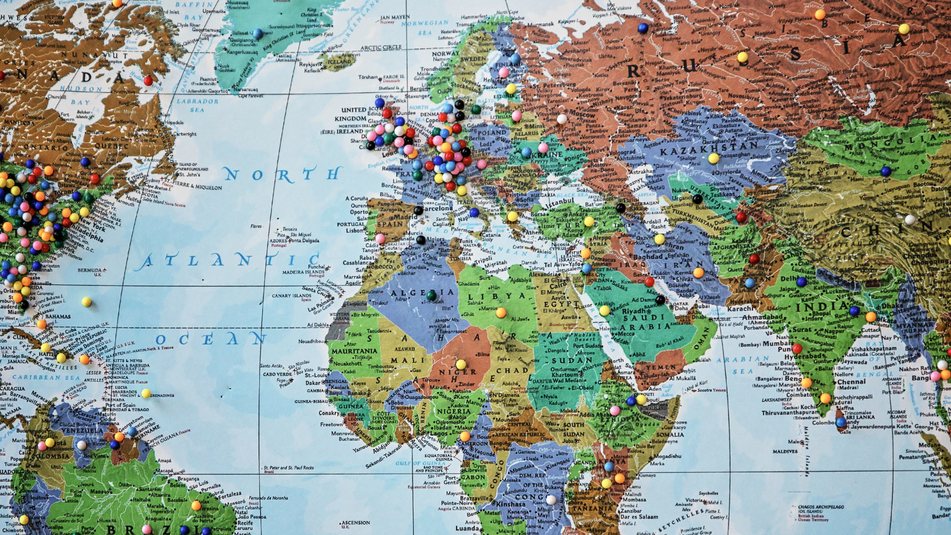 A world map with multi-colored pins put throughout on various countries.
