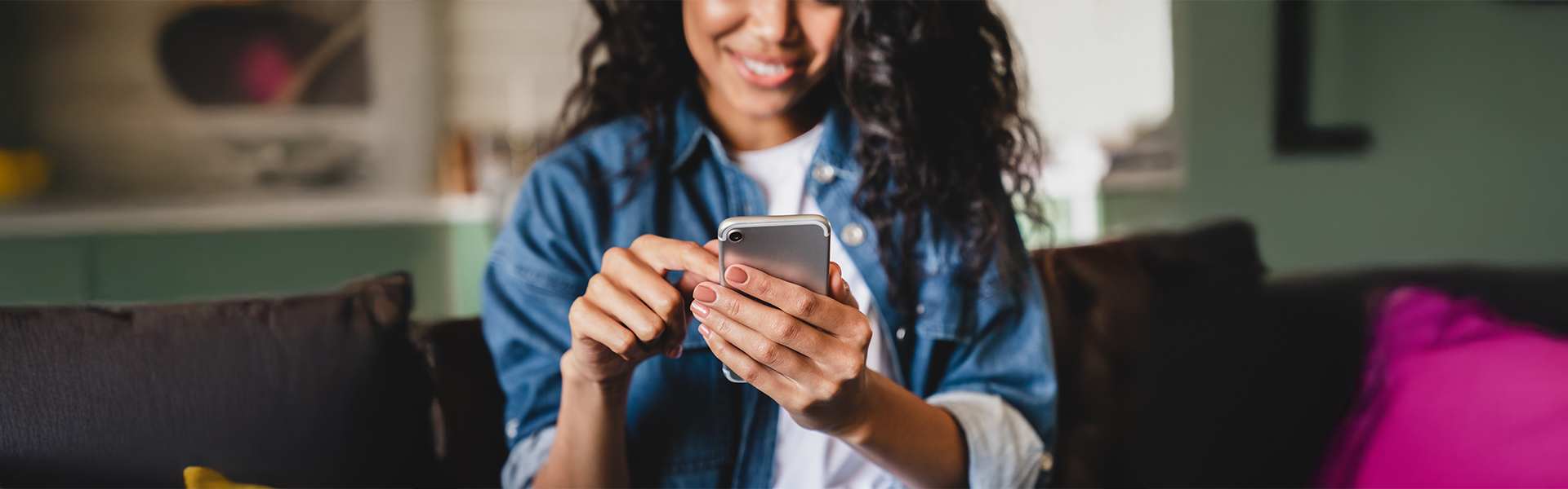 Woman using smartphone on couch, smiling and relaxed