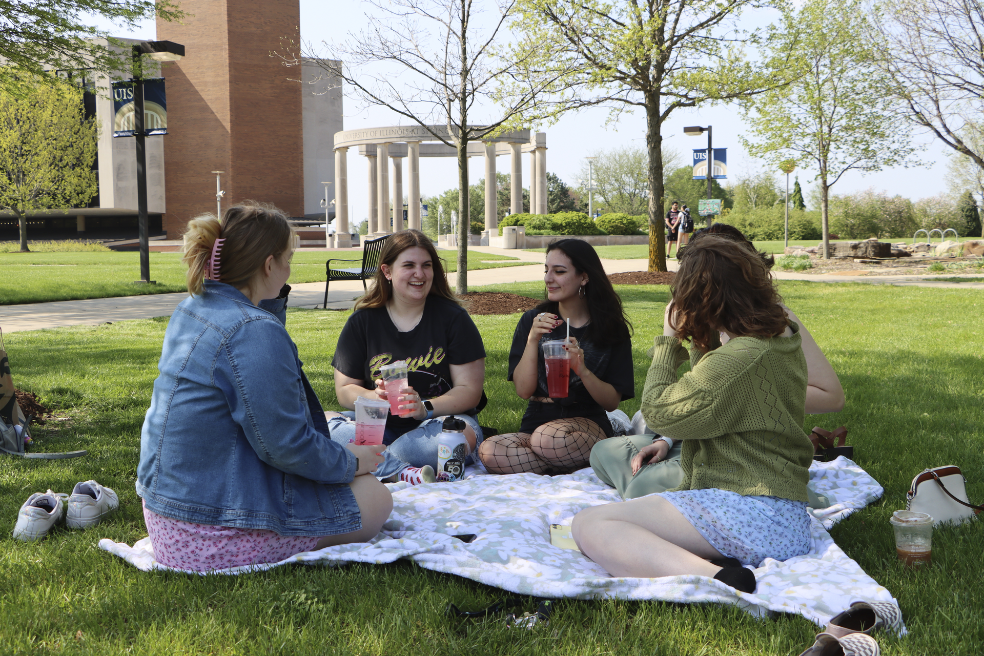 5 students sitting on the quad in front of the Colonnade