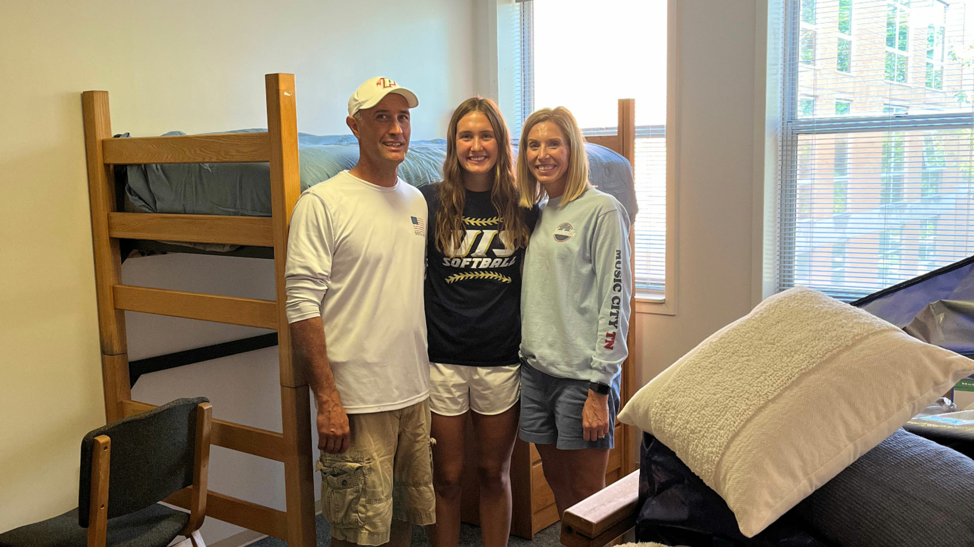 student and her parents in the student's dorm room