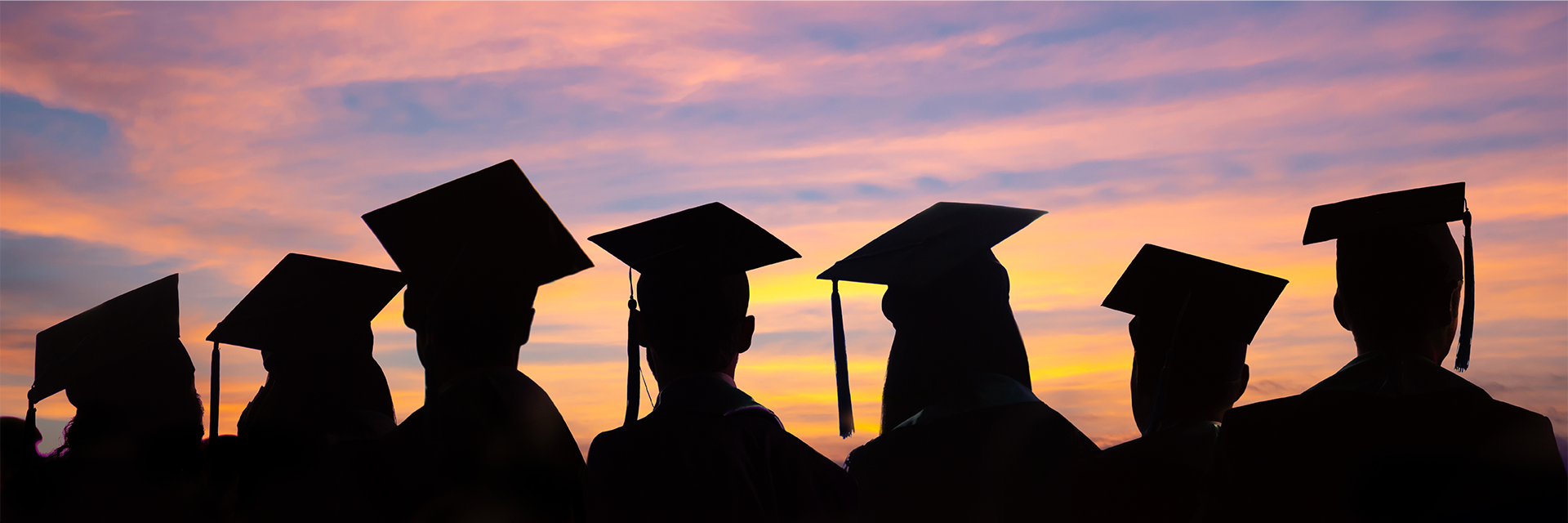 Graduation silhouettes at sunset with students in caps and gowns celebrating success