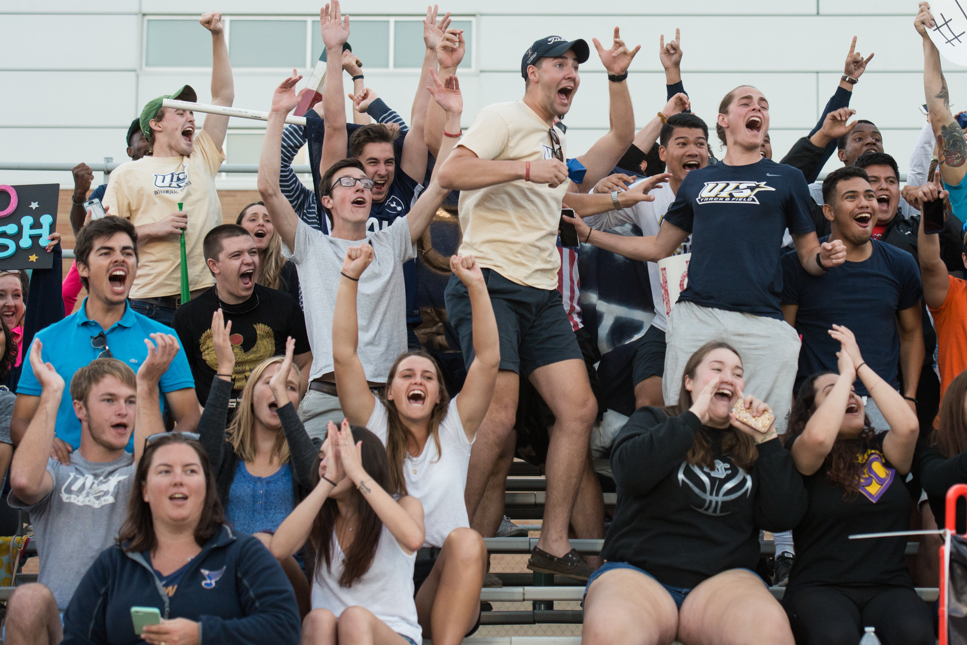 a crowd of people cheer from the stands at a UIS soccer game