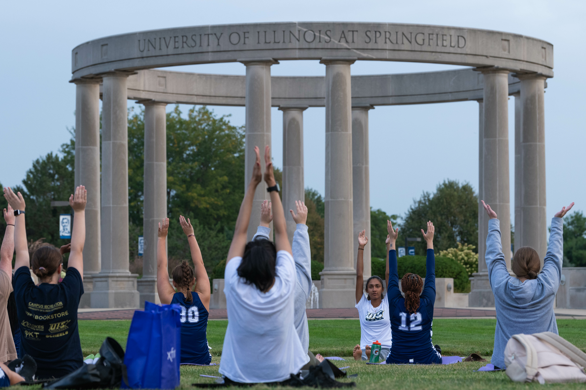 Student doing yoga on the quad in front of the colonnade 