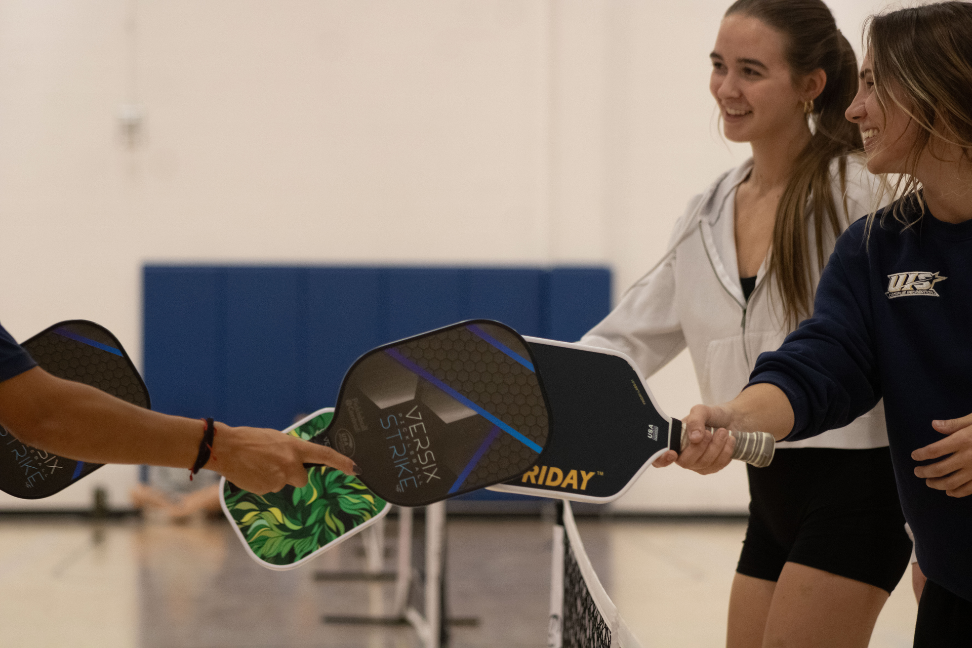 Students tapping pickleball paddles in the TRAC arena