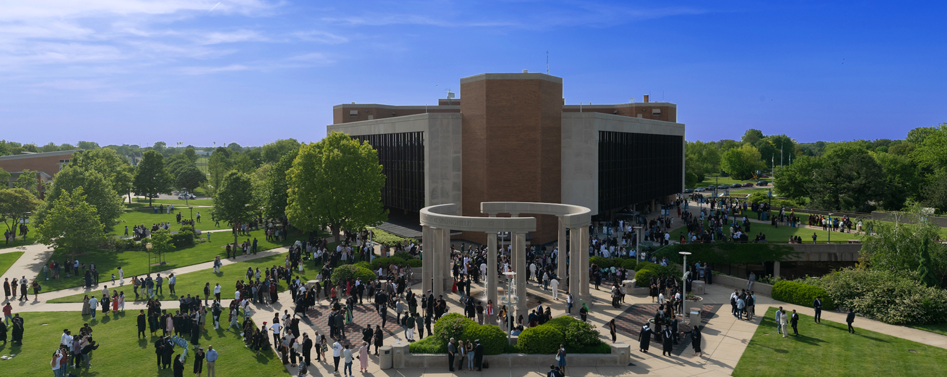 Graduates and families gather at the University of Illinois Springfield colonnade during commencement