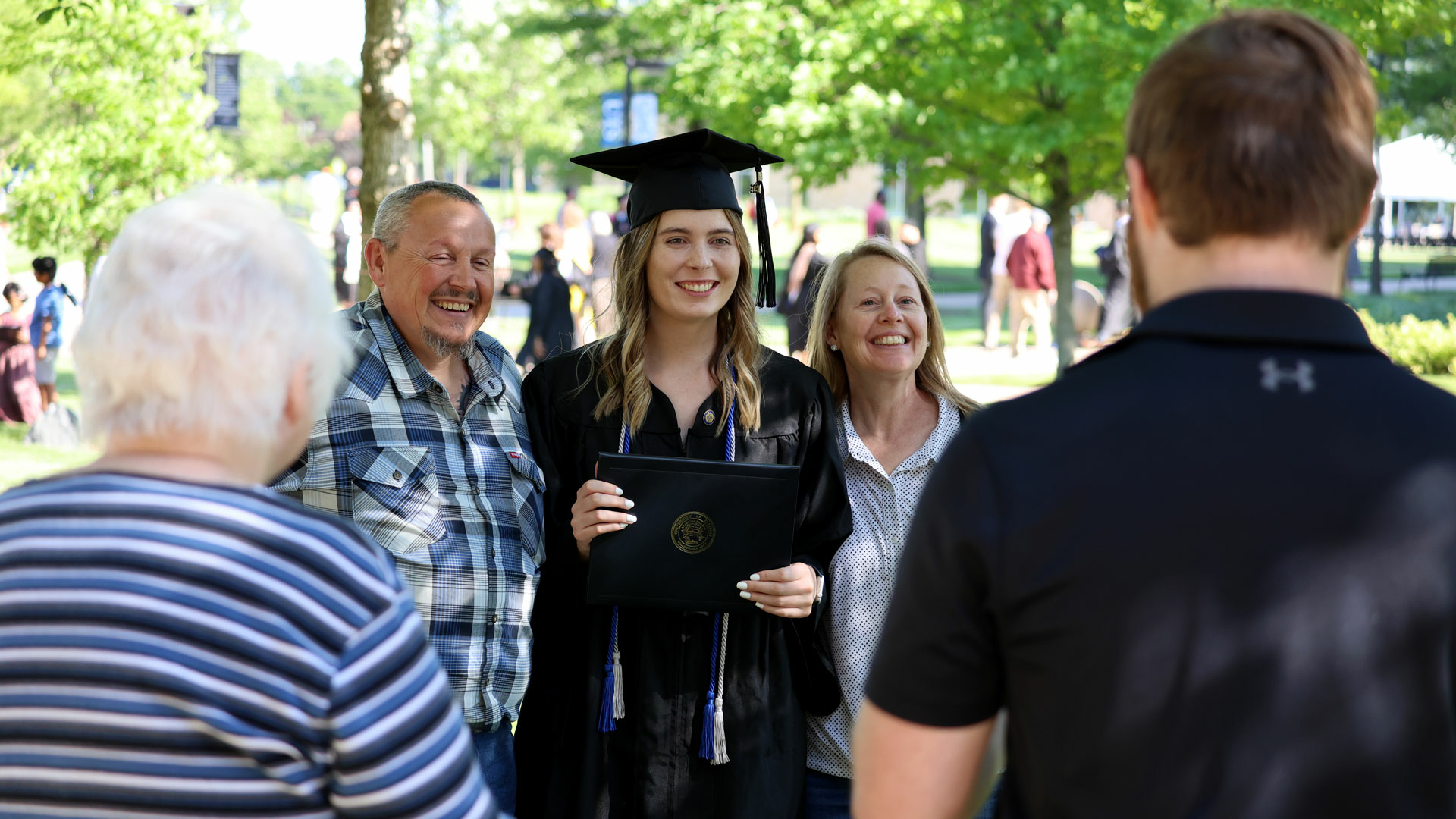 a female graduate in cap and gown posing with her parents